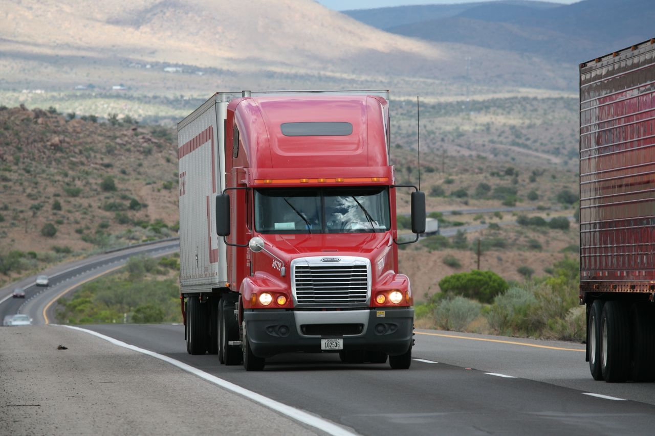 Crafting Captivating Headlines: Your awesome post title goes here Red semi-truck driving through scenic highway in a mountainous landscape.