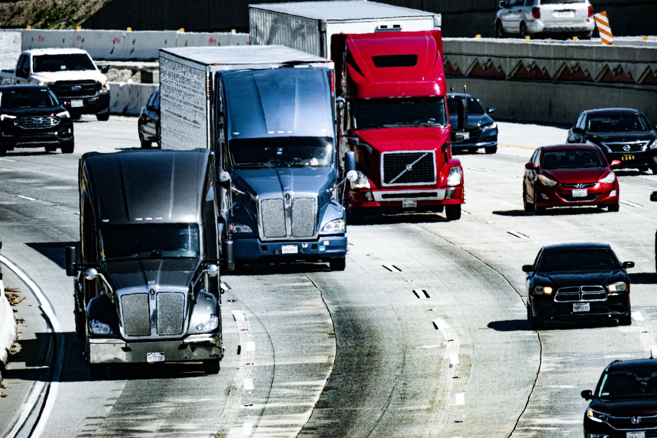 The Art of Drawing Readers In: Your attractive post title goes here Trucks and cars traveling on a congested city highway during the day.